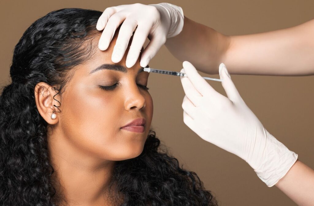 An esthetician carefully injects Botox between a patient's eyebrows.