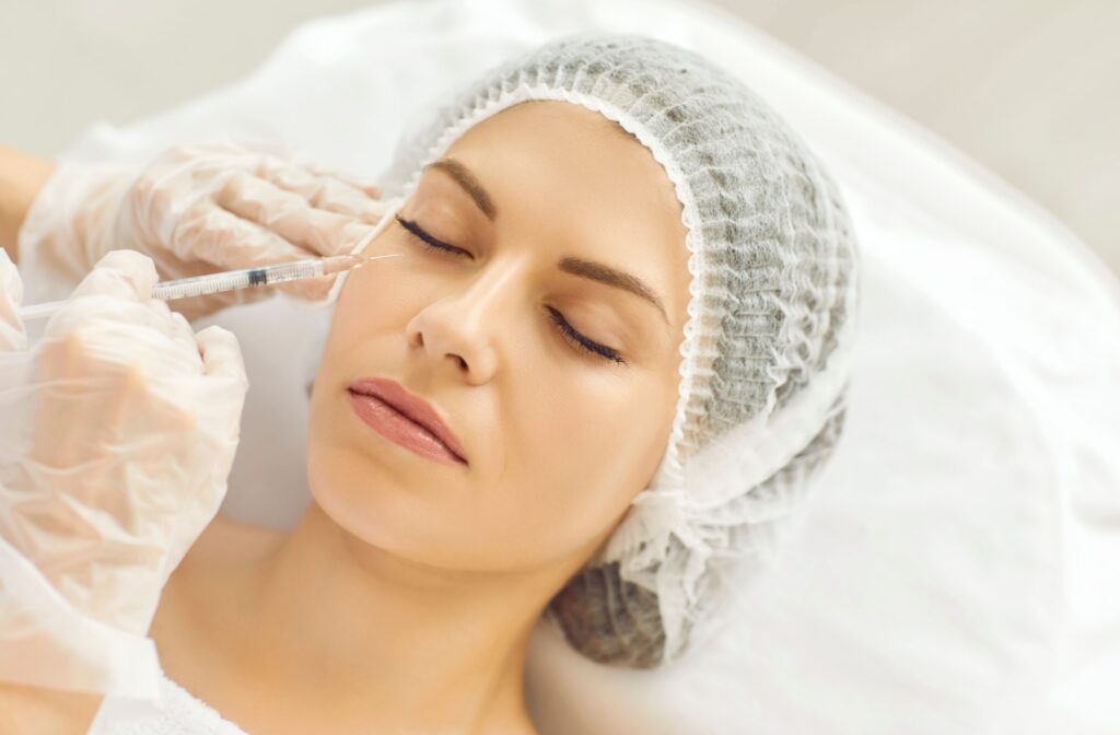 A practitioner gently injects dermal fillers into their patient's under-eye area to add volume.