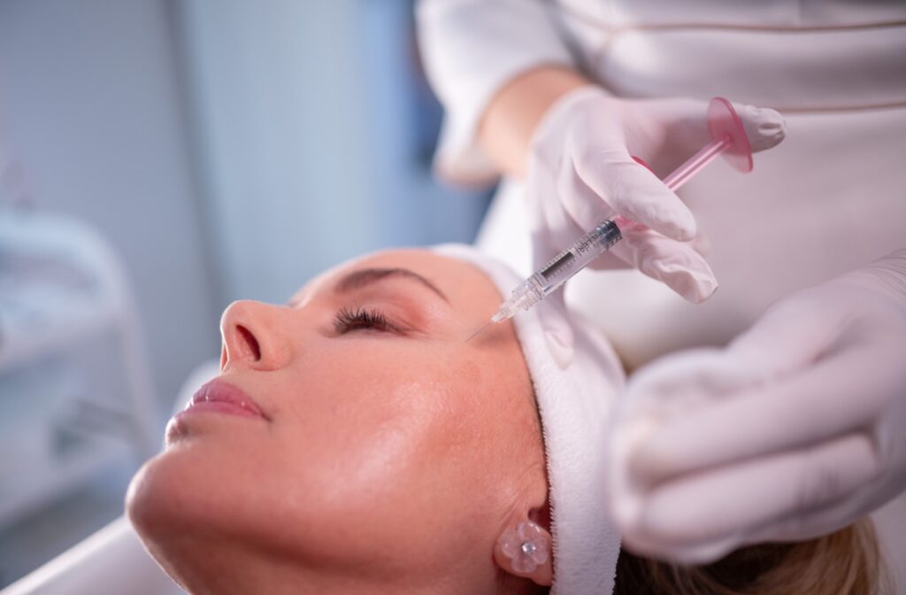A practitioner carefully injects Botox into a patient's temples.